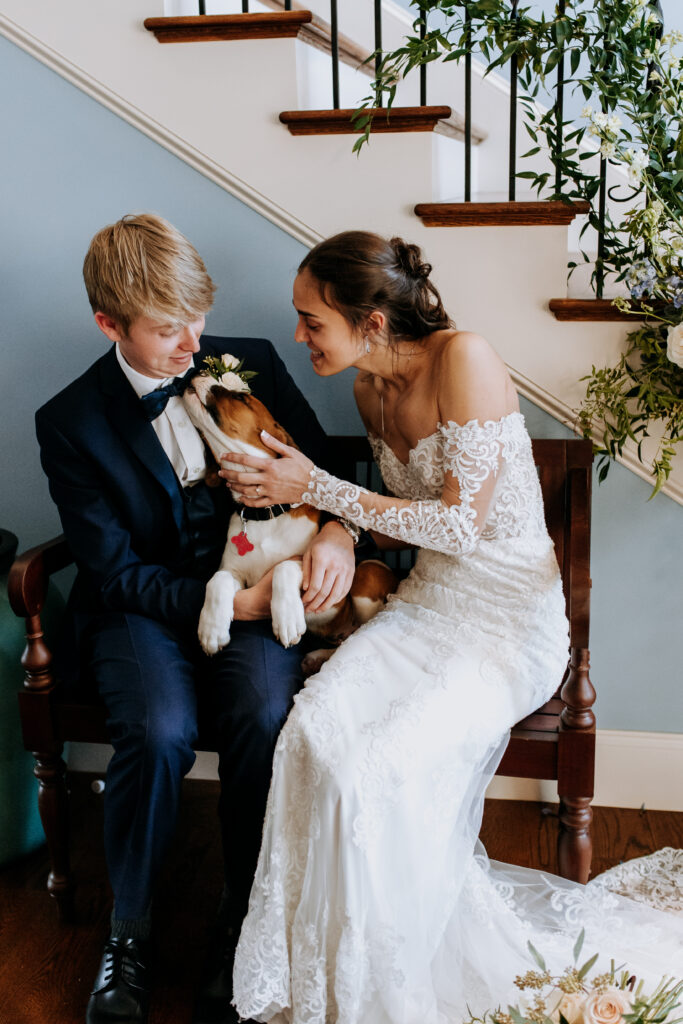 A bride and groom pet their puppy during a break from photos pet friendly wedding