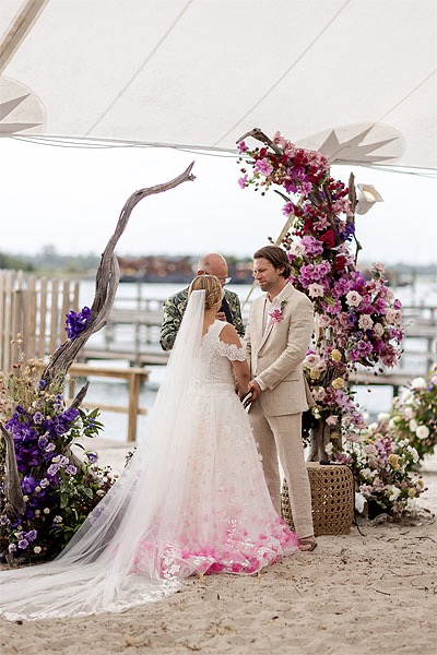 a wedding gown with fuchsia florals along the hem line trending wedding gowns 2025