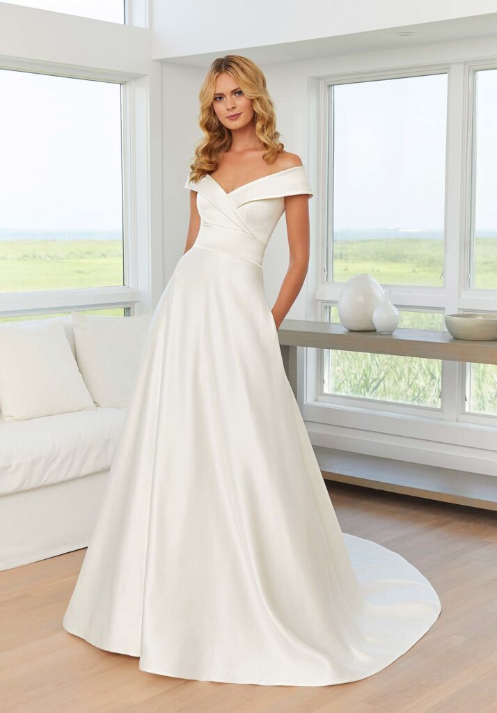 A bride wearing a trendy wedding gown portrait neckline 2025 wedding trends