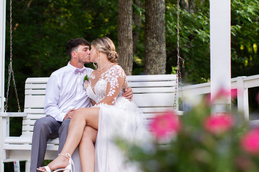 A bride and groom kiss on porch swing in Greenville county South Carolina Landrum wedding venue wedding down trends 2025