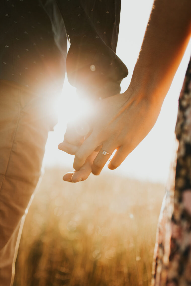 A couple holding hands with an engagement diamond ring