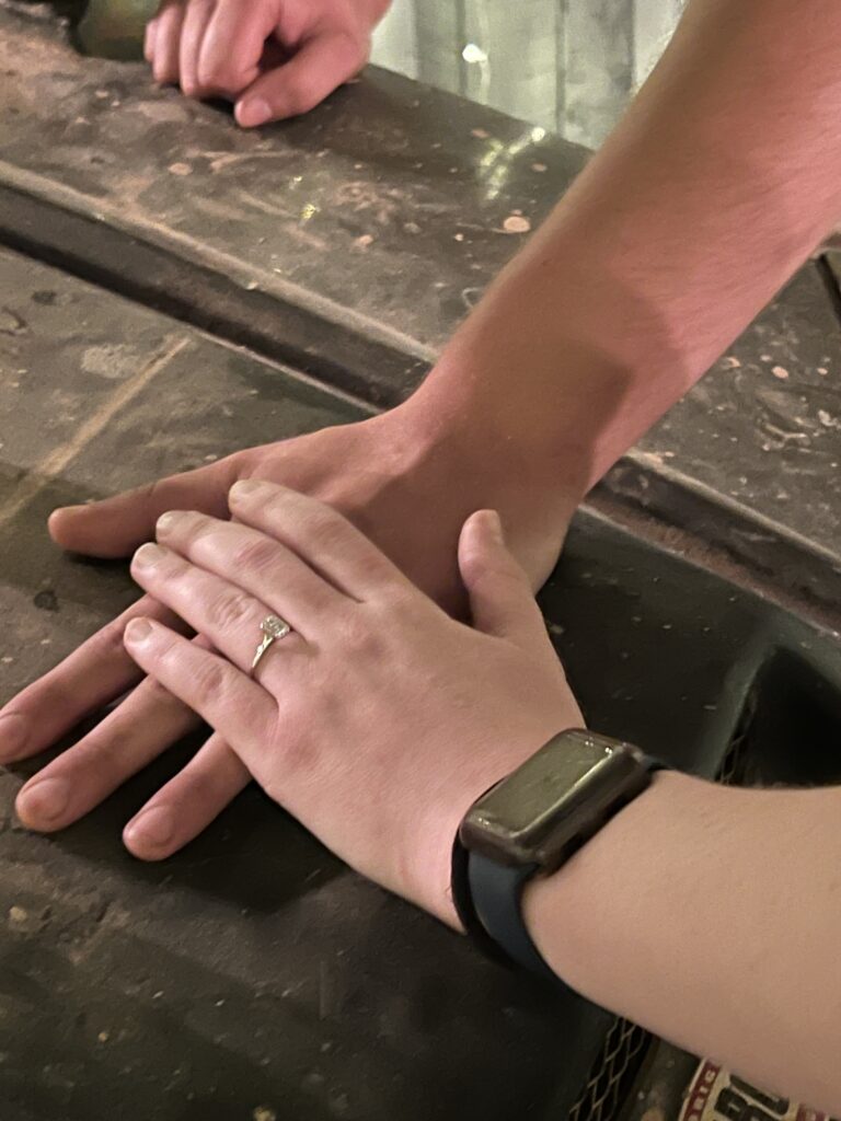  Newly engaged couple holding hands with the engagement ring as the subject of the photo in a summer engagement Greenville engagement