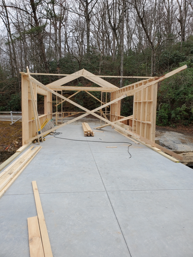Two opposing walls are braced by several pieces of lumber while the trusses are being installed for the roof. Of a locally owned upstate wedding venue covered bridge