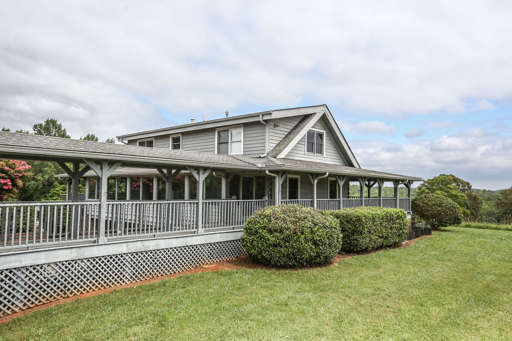 Exterior of on-site wedding venue lodging with a wraparound porch overlooking landscaped grounds.