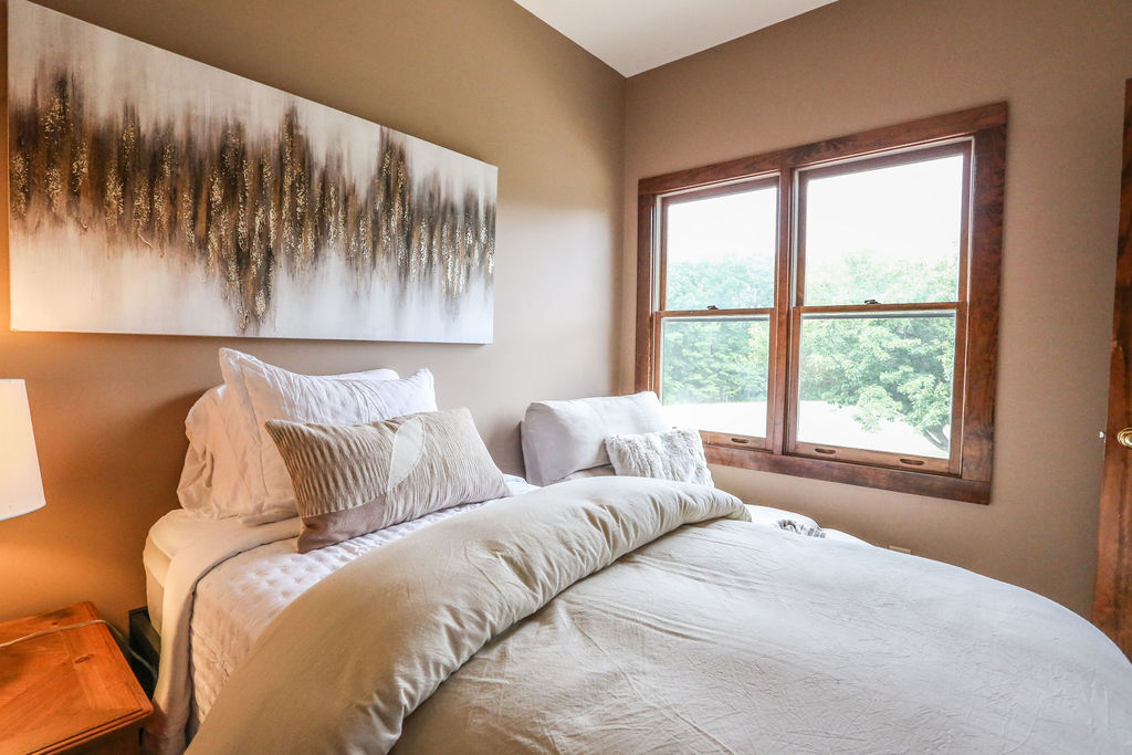  A twin bed and a Chase lounge with soft lamp light and a view of natural greenery out the window