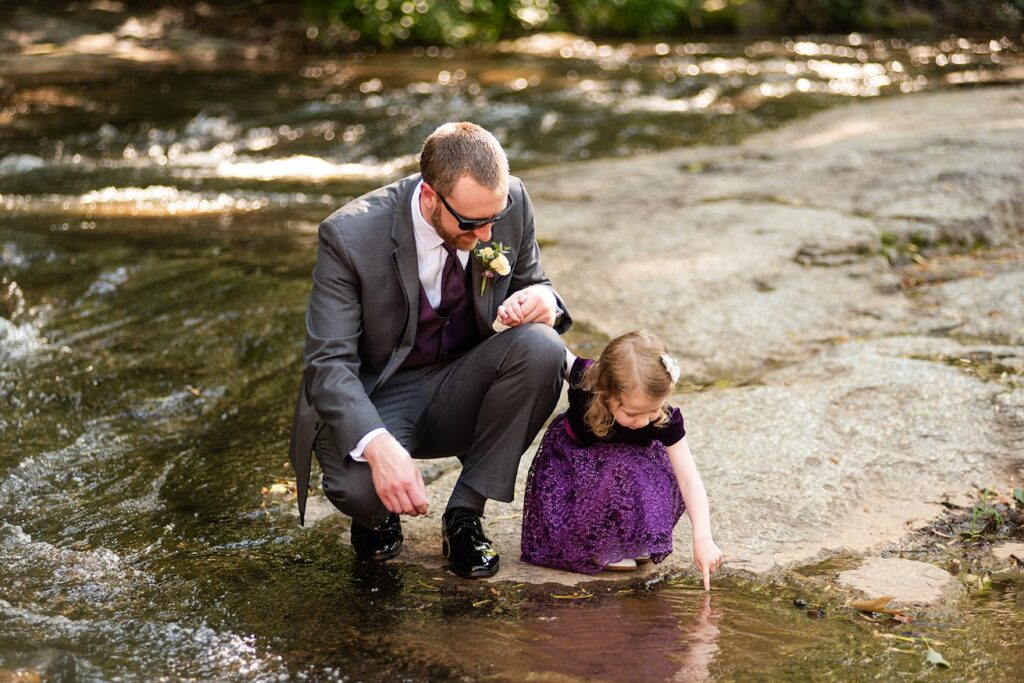 Groom and flower girl enjoying the river front wedding ceremony and natural beauty at this Greenville SC wedding venue