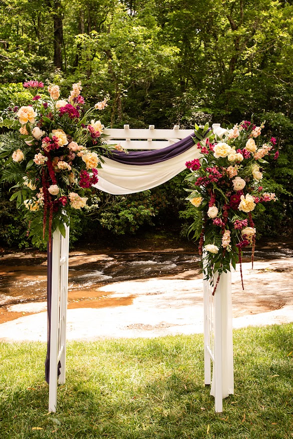 Outdoor wedding ceremony with arch covered in luxury flowers at a Greenville SC Wedding Venue near Spartanburg SC