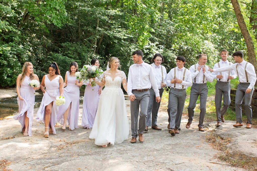Bride, Groom and wedding party pose for wedding days photos by the river at their garden wedding venue near Greenville SC
