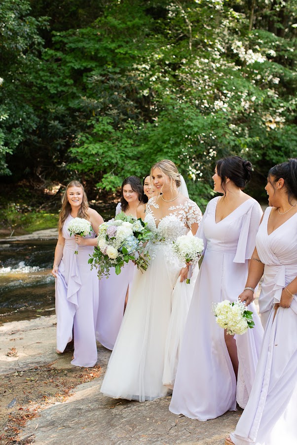 Bridesmaids wearing garden wedding dress code dresses by the river at a Greenville SC wedding venue