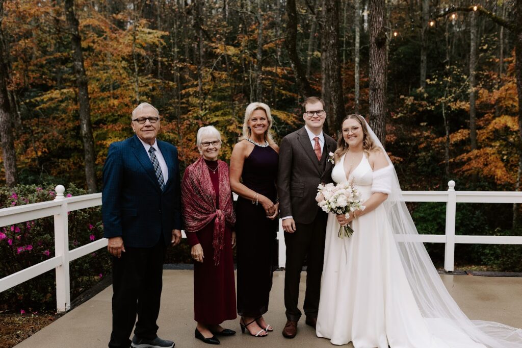 Bride and groom pose with wedding guests wearing semi formal wedding attire